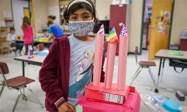 Student holds up a castle made out of recycled materials
